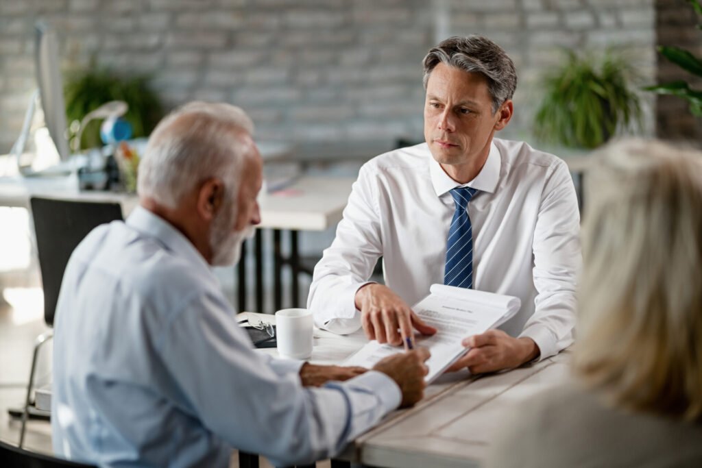 Herança e Sucessão: Como Planejar a Transmissão de Bens 1 insurance agent having meeting with senior clients pointing place signature contract Herança e Sucessão: Como Planejar a Transmissão de Bens